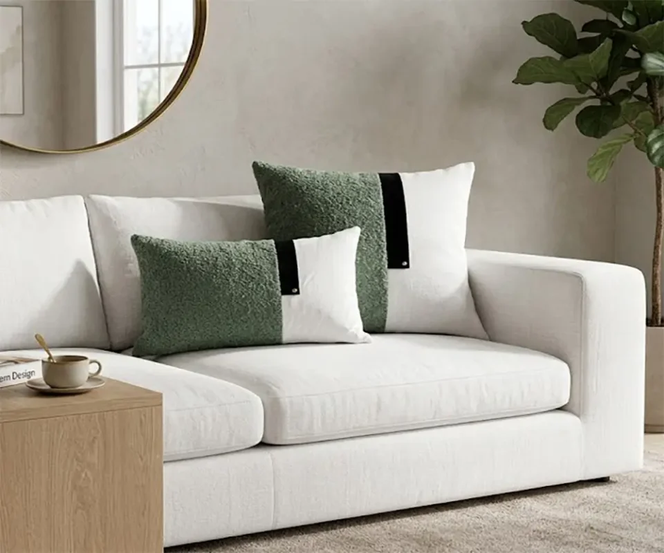Duo de coussins bicolores vert sauge en bouclette et blanc avec bande noire sur fond blanc.