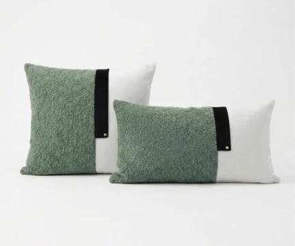 Duo de coussins bicolores vert sauge en bouclette et blanc avec bande noire sur fond blanc.