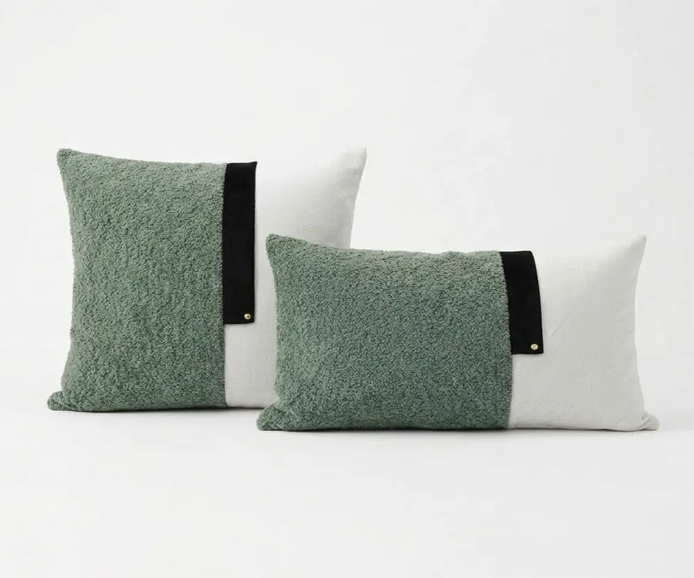 Coussin Sauge Duo de coussins bicolores vert sauge en bouclette et blanc avec bande noire sur fond blanc.